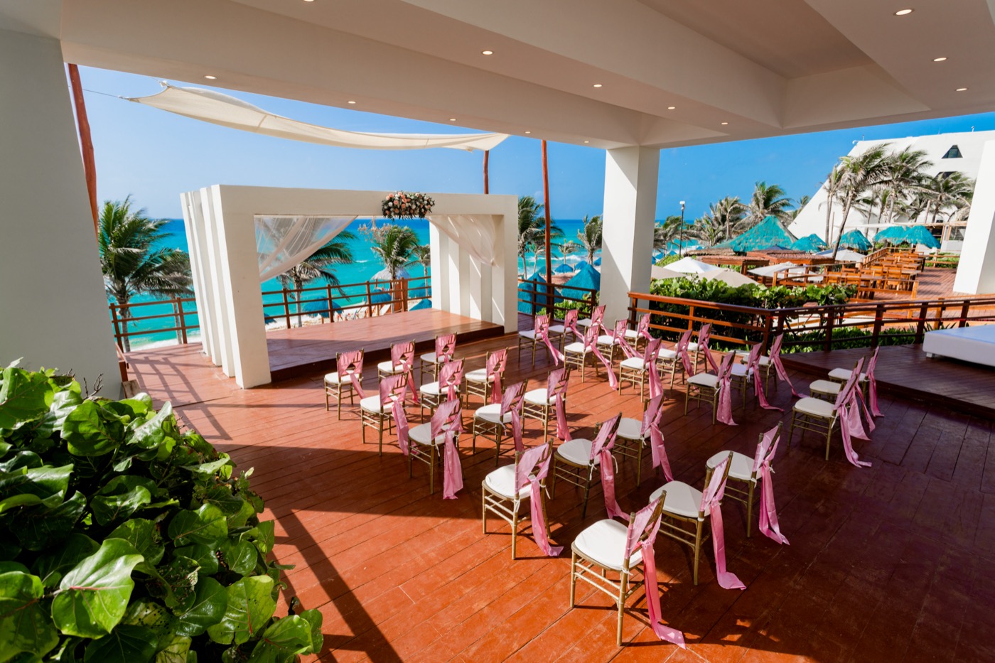 Altar en terraza con decoración de flores rojas con ramas junto al mar en el Hotel Grand Oasis Cancu