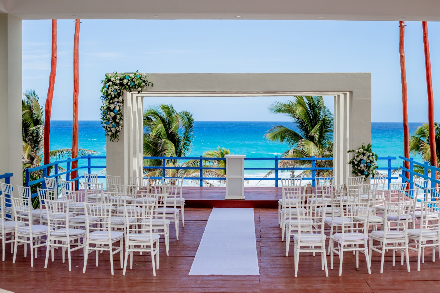 Altar en terraza con decoración de flores rojas con ramas junto al mar en el Hotel Grand Oasis Cancu