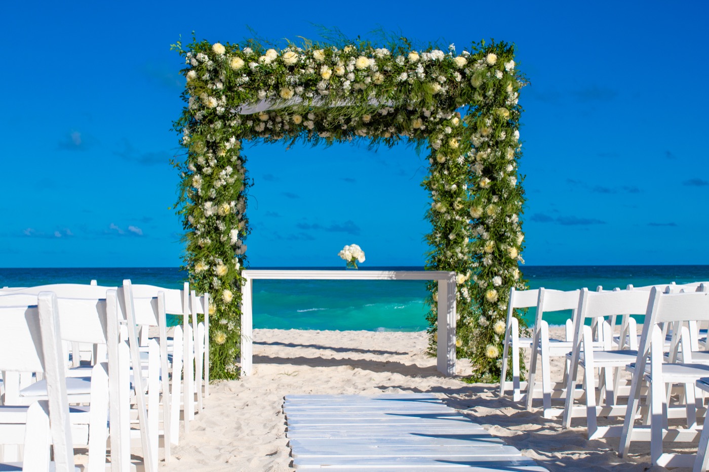 Altar en terraza con decoración de flores rojas con ramas junto al mar en el Hotel Grand Oasis Cancu